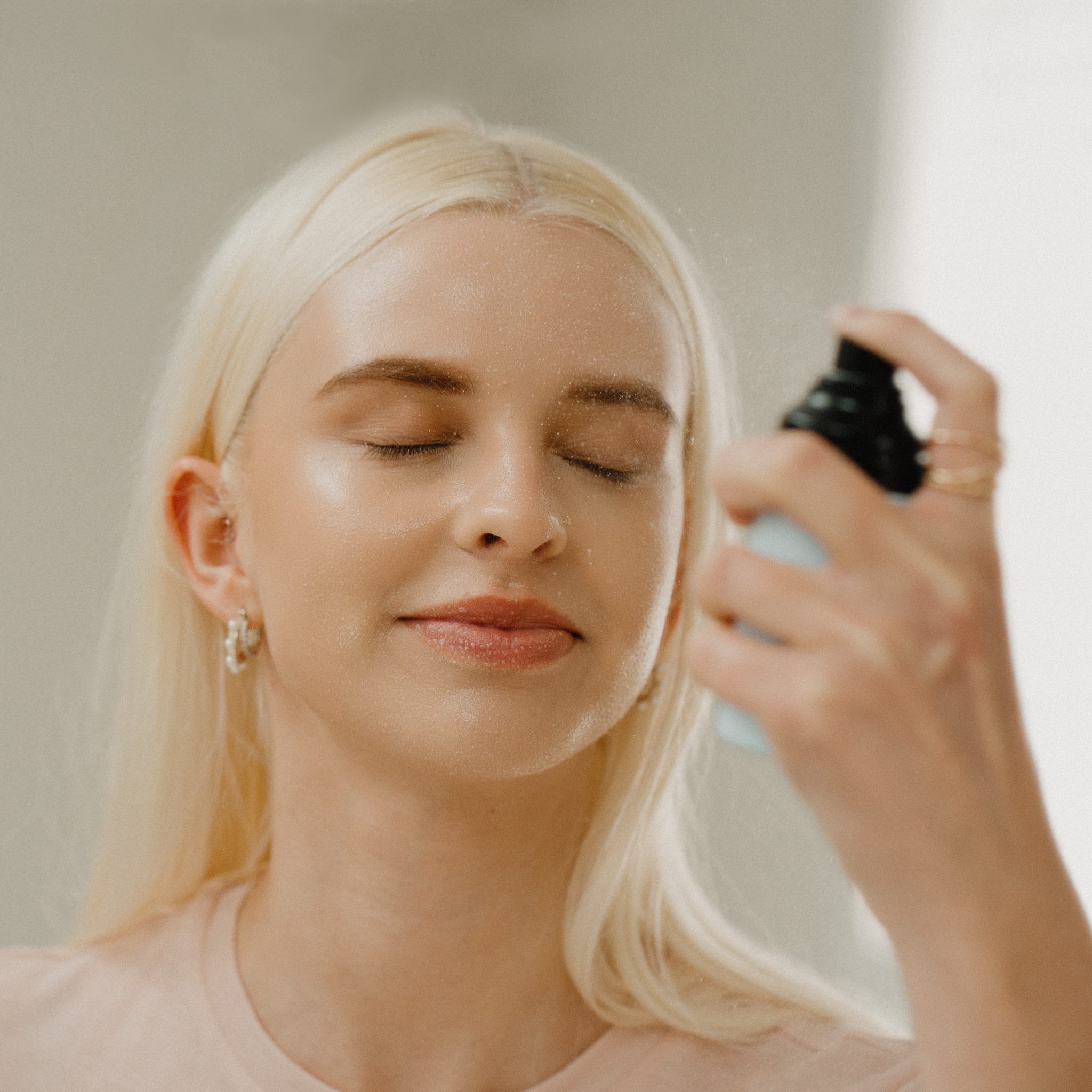 Girl misting spray on face