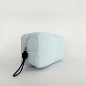 A soft‑touch corduroy bag Light blue textured pouch with a brand logo on a light gray background
