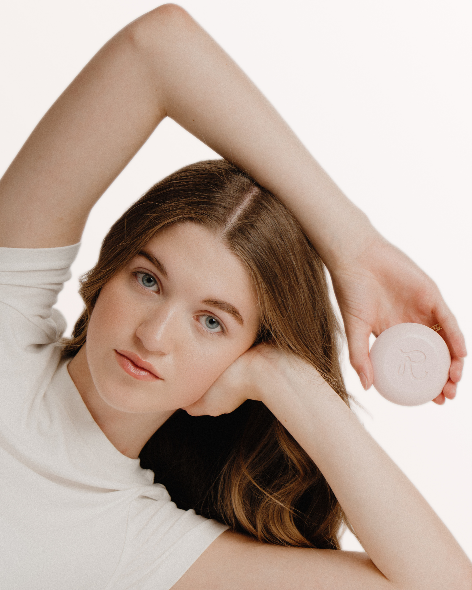 Woman holding a pink soap against a plain background