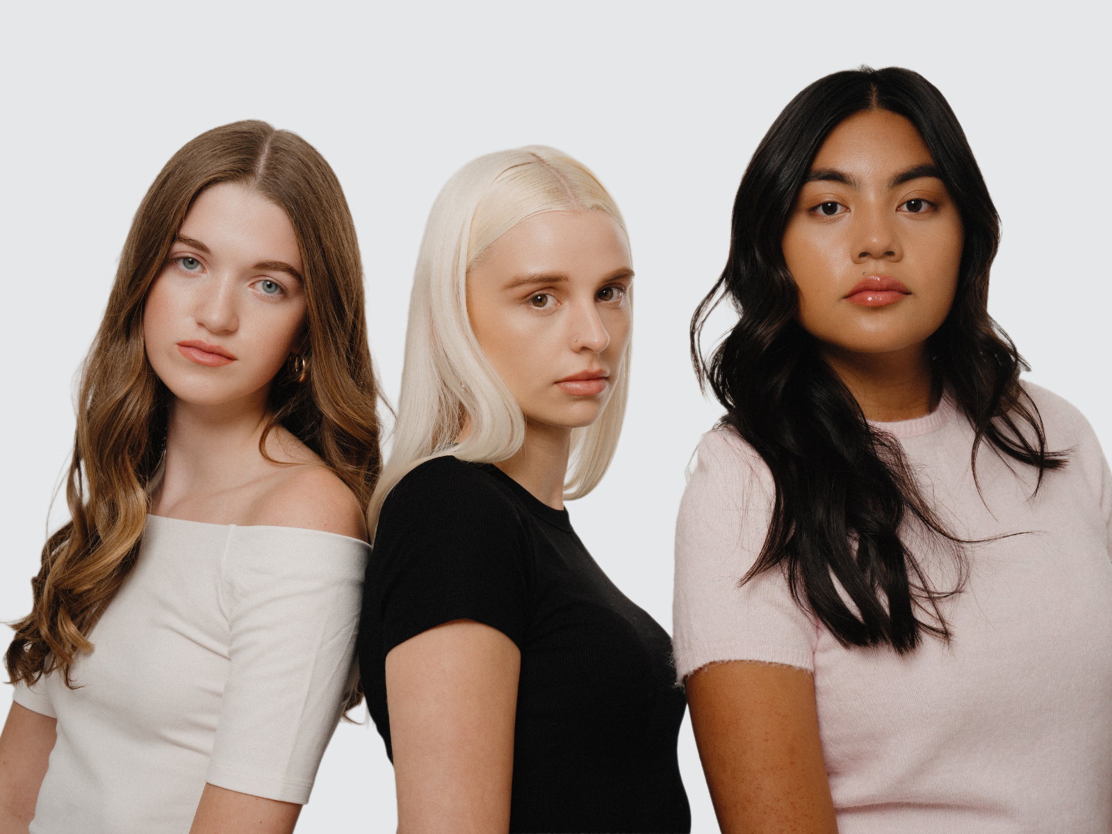 Three women with different hair colors standing side by side against a white background