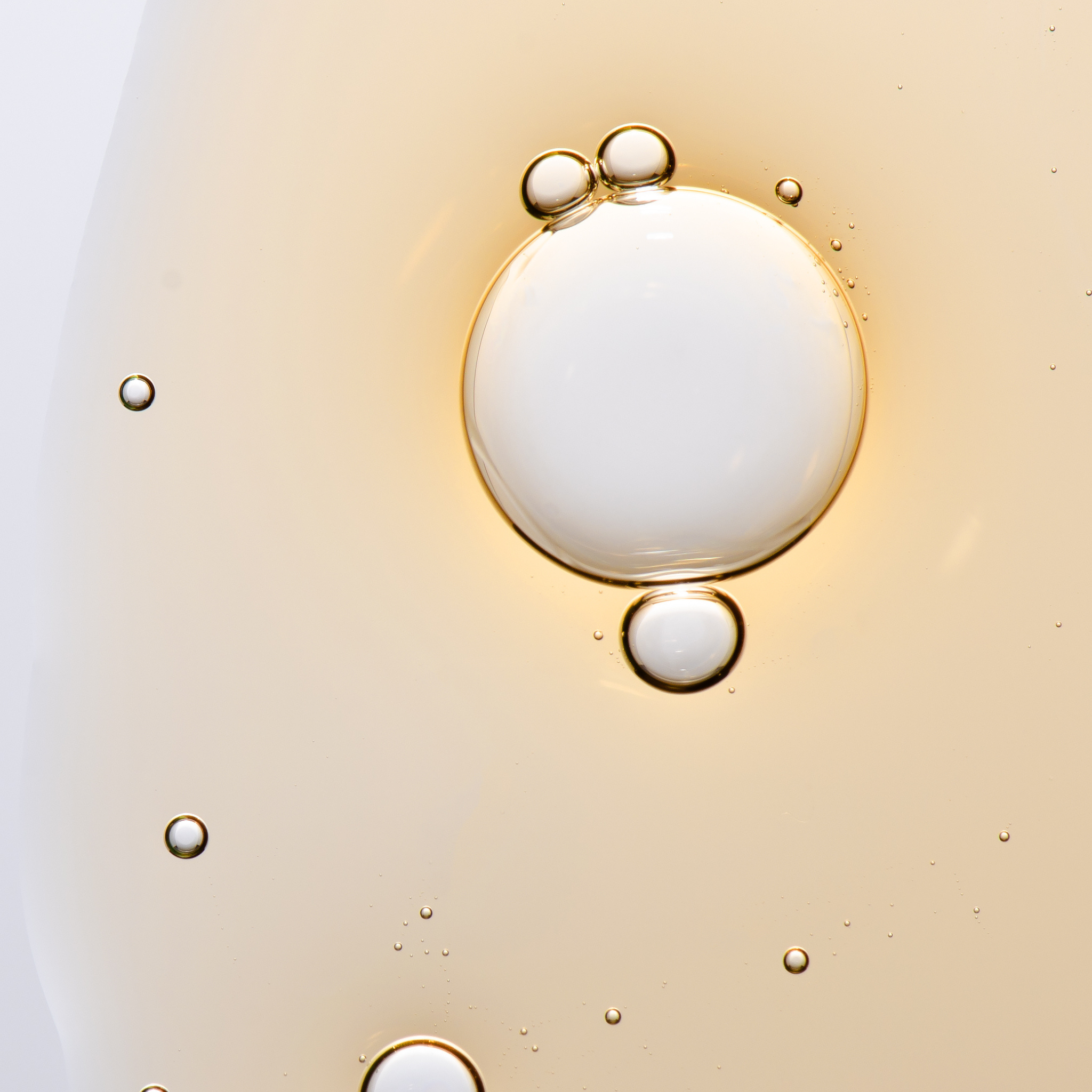 Close-up of oil droplets on a water surface with a light background
